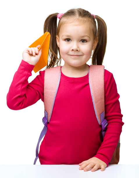 Schoolgirl with backpack throwing a paper airplane - Fotó, kép