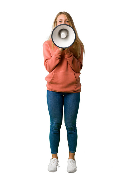 A full-length shot of a Young girl shouting through a megaphone to announce something on isolated white background - Fotografie, Obrázek
