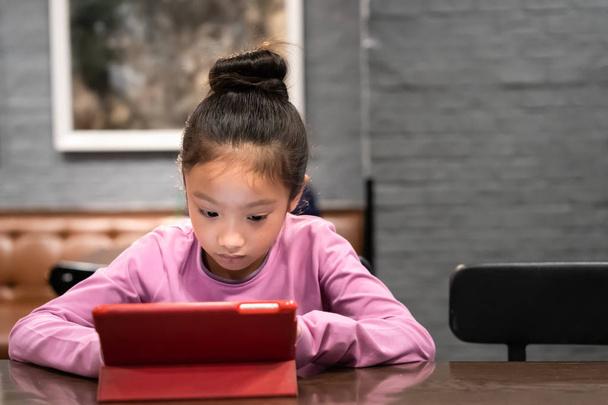 Kleines Mädchen schaut im Zimmer auf Tablet-Computer - Foto, Bild