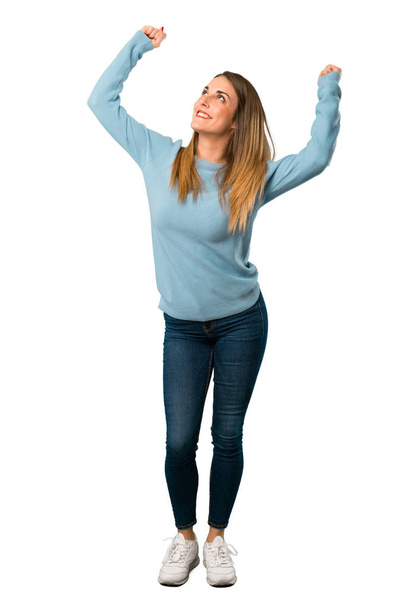 Full body of Blonde woman with blue shirt celebrating a victory in winner position on white background - Photo, Image