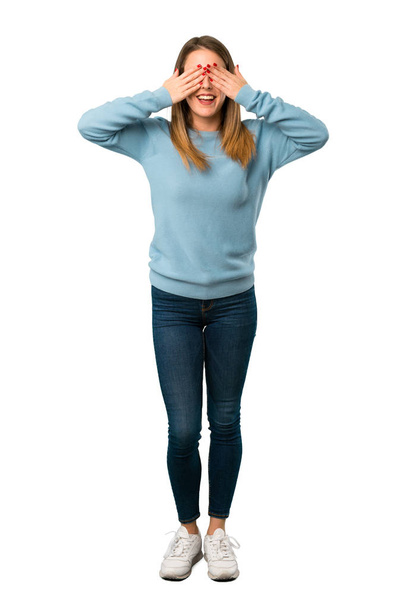 Full body of Blonde woman with blue shirt covering eyes by hands. Surprised to see what is ahead on white background - Fotó, kép