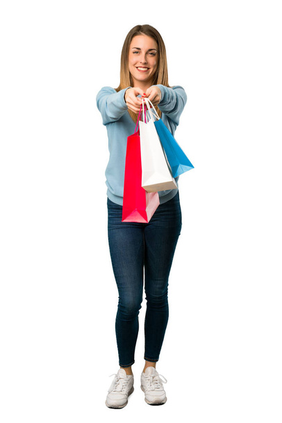 Full body of Blonde woman with blue shirt holding a lot of shopping bags on white background - Fotoğraf, Görsel