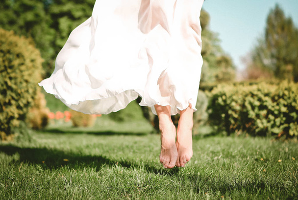 girl outside in a dress and barefoot jumped on the grass - Fotoğraf, Görsel