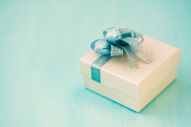Coffret cadeau en argent avec ruban bleu sur table bleue, cadeau pour donner en vacances
 - Photo, image