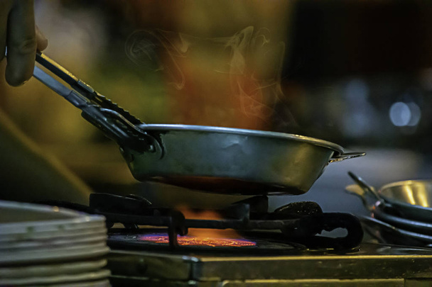 Сковорода из нержавеющей стали на плите с желтым пламенем
. - Фото, изображение