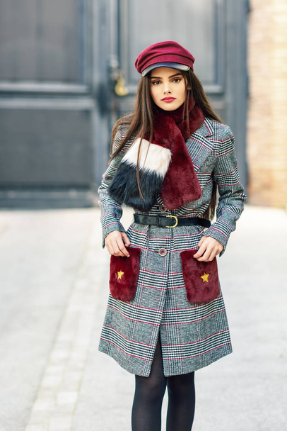 Spain, Andalusia, Granada. Young beautiful girl with very long hair looking at camera wearing winter coat and cap outdoors. Lifestyle and fashion concept. - Photo, image