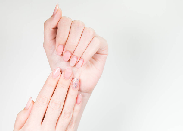 Detailní záběr na dvě ženské bílé ruce starý gel leštěné manikúra potřebují opravu po několika týdnech nošení. Vertikální barevné fotografie. - Fotografie, Obrázek