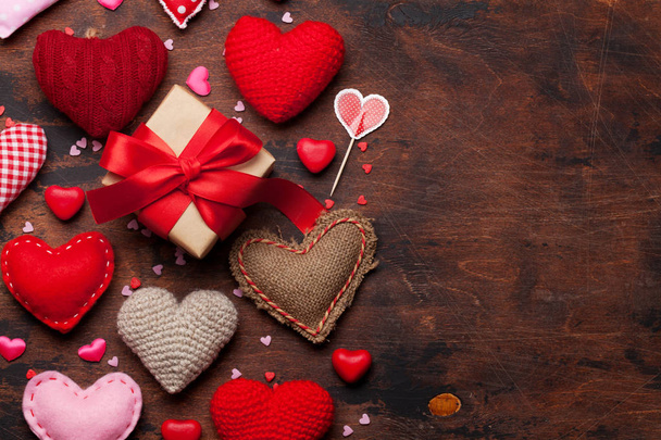 Tarjeta de felicitación del día de San Valentín con juguetes de corazón hechos a mano y caja de regalo de amor sobre fondo de madera. Vista superior con espacio para sus saludos. Puesta plana
 - Foto, imagen
