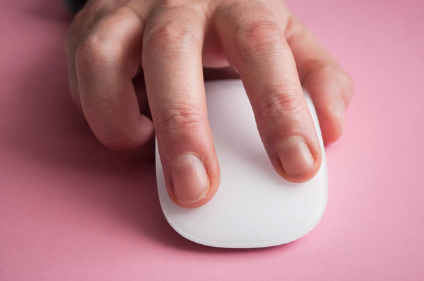 closeup of hand of man on white mouse on pink background  - Photo, image