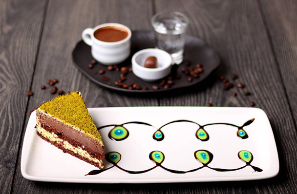 Delicious chocolate cake with a layer of green pistachio and Turkish coffee in the background - Photo, Image