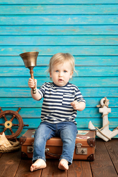 Happy toddler holding bell playing sailing at home, summer vacation and travel concept. - Фото, изображение