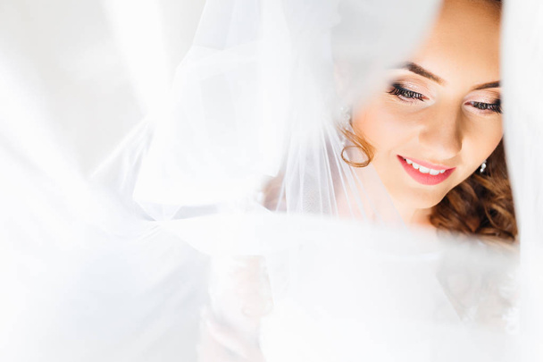 το πρόσωπο της νύφης, κοιτάζοντας προς τα κάτω και τούλι γύρω από το πρόσωπο - Φωτογραφία, εικόνα