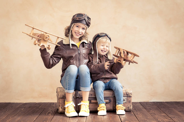 Happy children playing with vintage wooden airplane. Kids having fun at home. Imagination and freedom concept - Foto, Bild