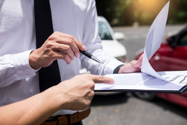 Agente de seguros escrevendo na área de transferência enquanto examina carro após pedido de acidente a ser avaliado e processado
 - Foto, Imagem