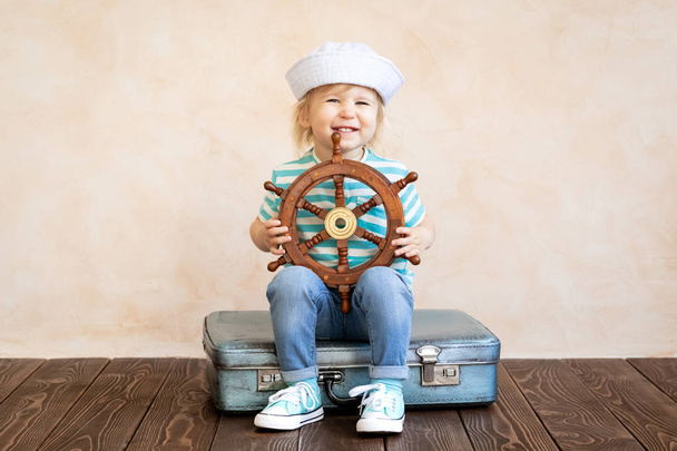 Happy toddler holding wheel while playing sailing at home, summer vacation and travel concept. - Фото, зображення