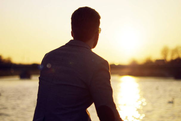 Silhouette eines Mannes. Sonnenuntergang See und Fluss Natur Hintergrund schönen Himmel. Geschäftsmann blickt in die Ferne und grübelt, denkt, träumt. - Foto, Bild