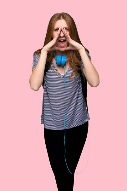 Redhead student woman shouting and announcing something on isolated pink background - 写真・画像