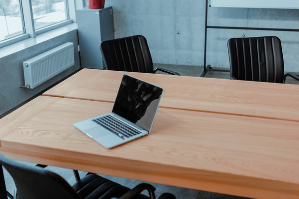 Large bright office in a loft style, with windows, concrete walls and a laptop on a wooden table - Photo, Image