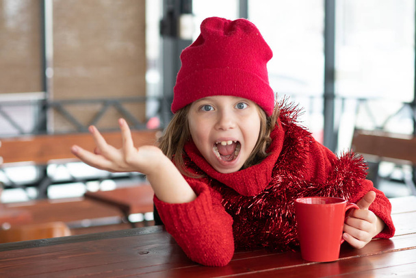 little girl sitting in a cafe at christmas - Foto, imagen