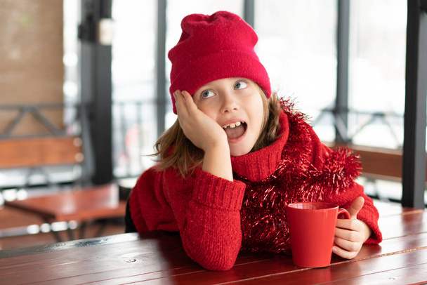 niña sentada en un café en Navidad
 - Foto, Imagen