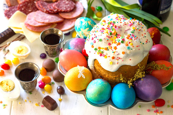 Comida de Pascua Desayuno. Pastel de Pascua, huevos pintados y deliciosa delicatessen en mesa de madera blanca
. - Foto, imagen