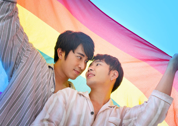 Гей пара сладкий и романтический момент под радужным флагом или флагом ЛГБТ
. - Фото, изображение