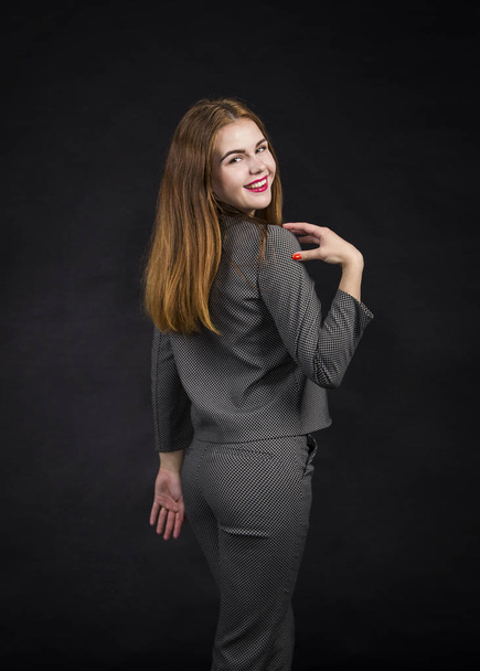Red-haired girl with long hair in a pantsuit. Posing in the Studio on a dark background. - Foto, Bild