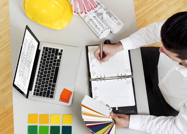 Man working on construction papers at desk - Photo, Image