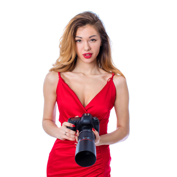 Happy blonde photographer woman in sexy red dress holding camera, isolated on white background - Foto, immagini