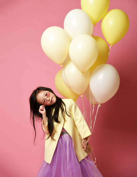 Little Korean baby girl in yellow fashion jacket and purple dress with balloons celebrate happy smiling - Foto, Imagen