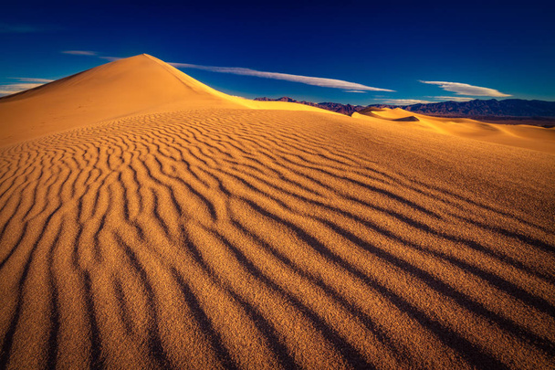 Tämä on valokuva Death Valleyn kansallispuistosta, jossa on hiekkadyynikuvioita.
 - Valokuva, kuva