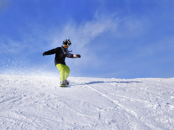 Сноубордист на склоне в голубом небе
. - Фото, изображение