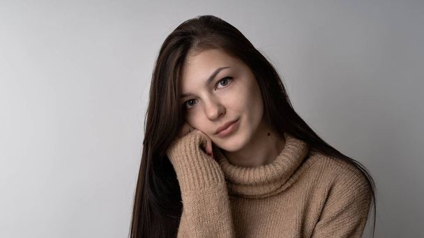 Hermosa joven morena mujer en suéter de punto cálido sobre fondo gris claro
 - Foto, imagen