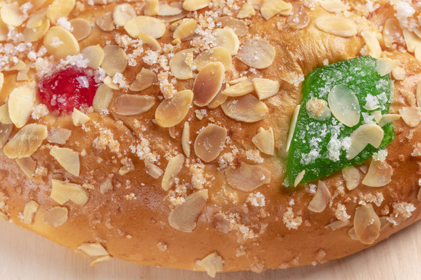 Torta tipica spagnola dell'Epifania Roscon de Reyes con frutta su fondo di legno
 - Foto, immagini