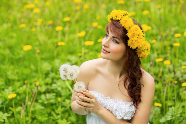 beautiful girl with dandelion flowers in green field - Zdjęcie, obraz