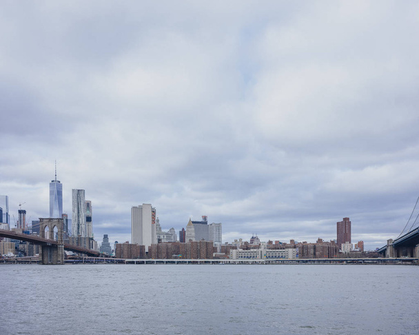 Ορίζοντας του Μανχάταν πάνω από τον ποταμό ανατολικά, στην πόλη της Νέας Υόρκης, ΗΠΑ, είδαν από το Μπρούκλιν με γέφυρα του Μπρούκλιν - Φωτογραφία, εικόνα