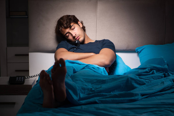 Yatakta telefonda konuşan genç adam - Fotoğraf, Görsel