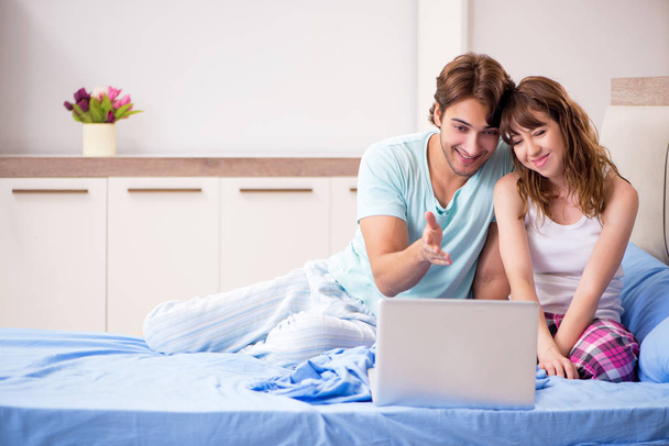 Giovane coppia con computer portatile in camera da letto
  - Foto, immagini