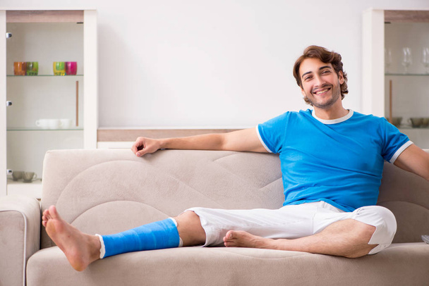 Leg injured young man on the sofa - Photo, image