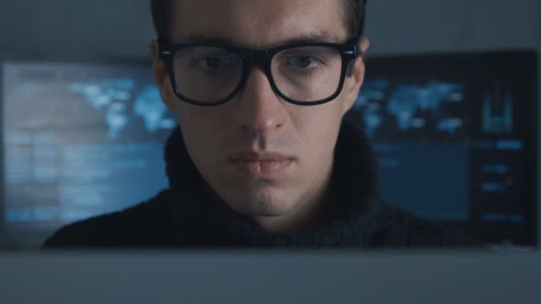 Retrato de programador profesional de TI en gafas está trabajando en la computadora en el centro de seguridad cibernética lleno de pantallas
. - Metraje, vídeo