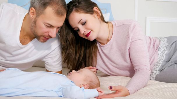 Glückliche Eltern blicken auf süßes schlafendes Baby im Schlafzimmer - Foto, Bild
