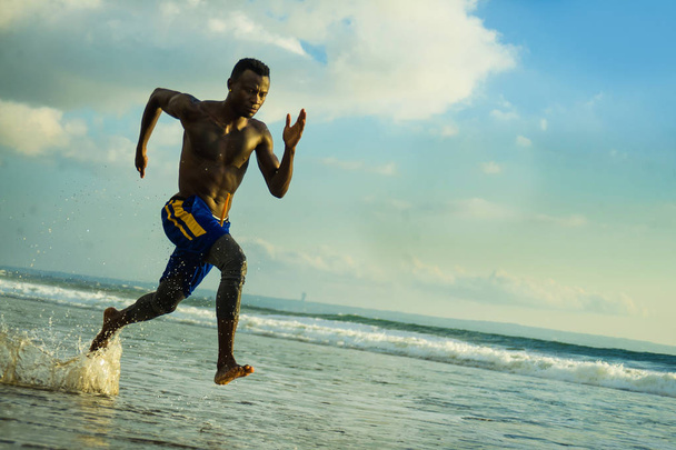 young attractive fit athletic and strong black afro American man running at the beach training hard and sprinting on sea water in professional athlete lifestyle and ripped runner workout  - Foto, immagini