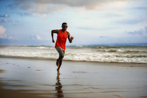 młody atrakcyjny pasują sportowe i silne czarne African American człowiek działa na plaży szkolenia twarde i Sprint na wodę morską w stylu życia zawodowego sportowca i zgrywanie treningu biegacza  - Zdjęcie, obraz