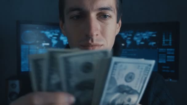 Portrait d'un programmeur de pirate compte l'argent gagné ith criminellement sur Darknet dans le centre de cybersécurité rempli d'écrans d'affichage
. - Séquence, vidéo
