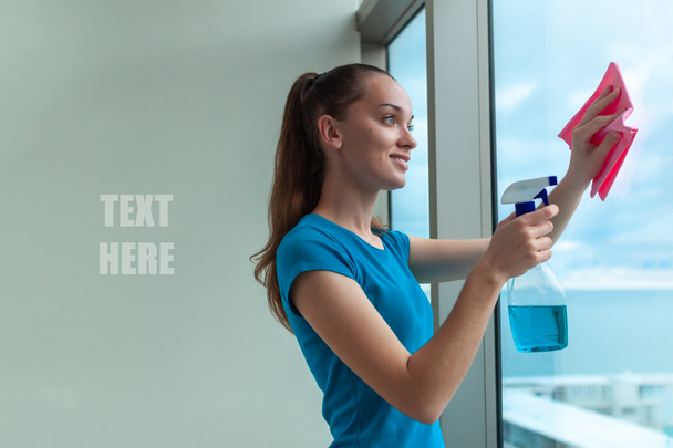 Una giovane casalinga con una maglietta blu lava le finestre della casa con uno straccio e uno spray per pulire gli occhiali. Pulisco la casa. Ricevuto. faccende domestiche
 - Foto, immagini