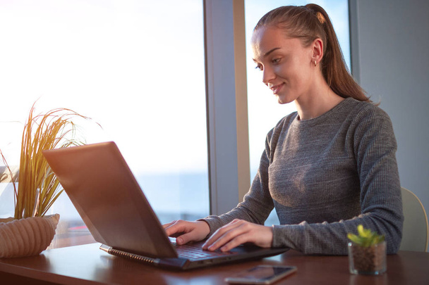 Красива молода бізнес-леді сидить на робочому місці, використовуючи ноутбук для роботи в Інтернеті і друку на клавіатурі
  - Фото, зображення