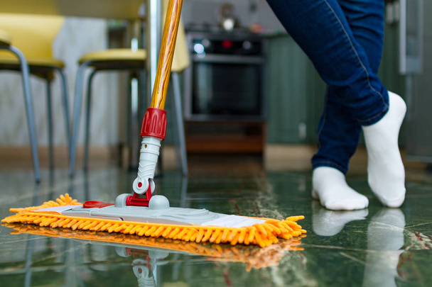 Η νοικοκυρά ασχολείται με την καθαριότητα του σπιτιού, σφουγγάρισμα. Καθαριότητα σπιτιού, όροφος πλυντήριο. Οικιακές δουλειές - Φωτογραφία, εικόνα