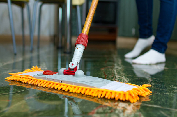 De huisvrouw houdt zich bezig met het schoonmaken van het huis, dweilen. Home reiniging, wassen van de vloer. Huishoudelijke taken - Foto, afbeelding