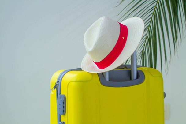 Yellow suitcase, hat and palm branch for a vacation trip. Vacation planning - Foto, Imagem