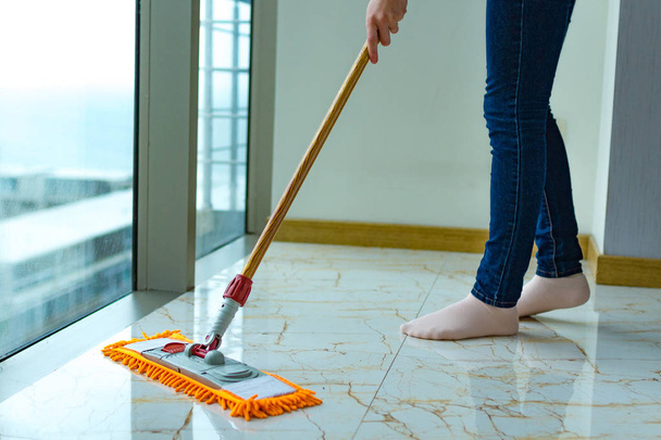 A dona de casa está a limpar a casa, a limpar o chão. Trabalho doméstico, tarefas domésticas. Lavagem do chão
 - Foto, Imagem